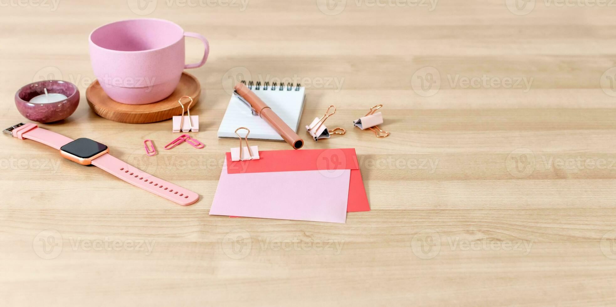 Office desk with tea cup, notebook, pen, card and envelope. Wooden desktop. photo