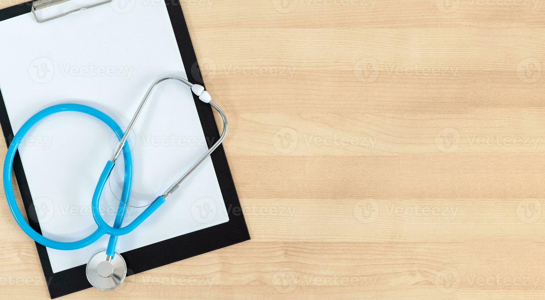 Medical clipboard and stethoscope on wooden desk background. Top view. Workplace of a doctor. photo