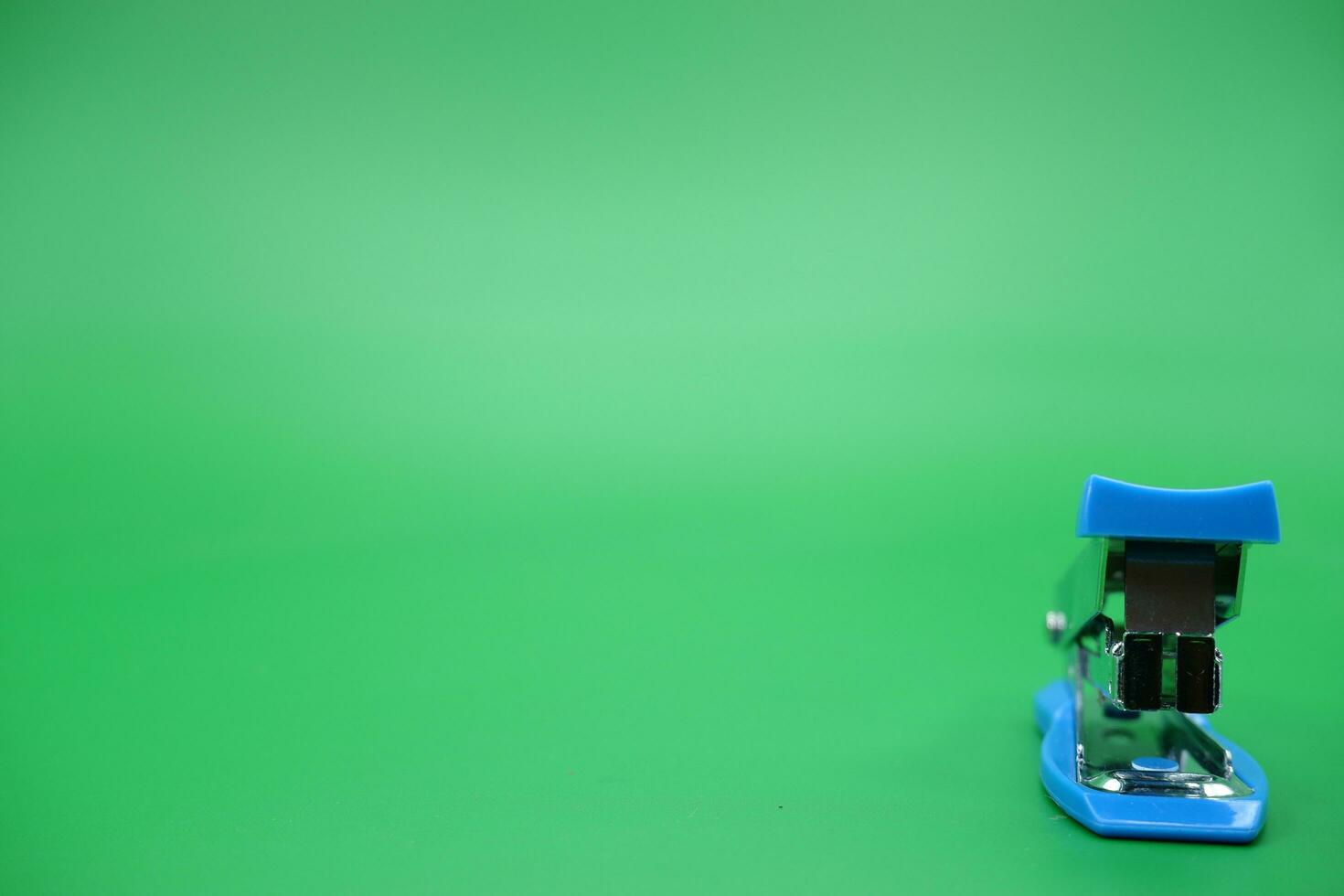 stapler isolated green background. Front view of the mini stapler. photo