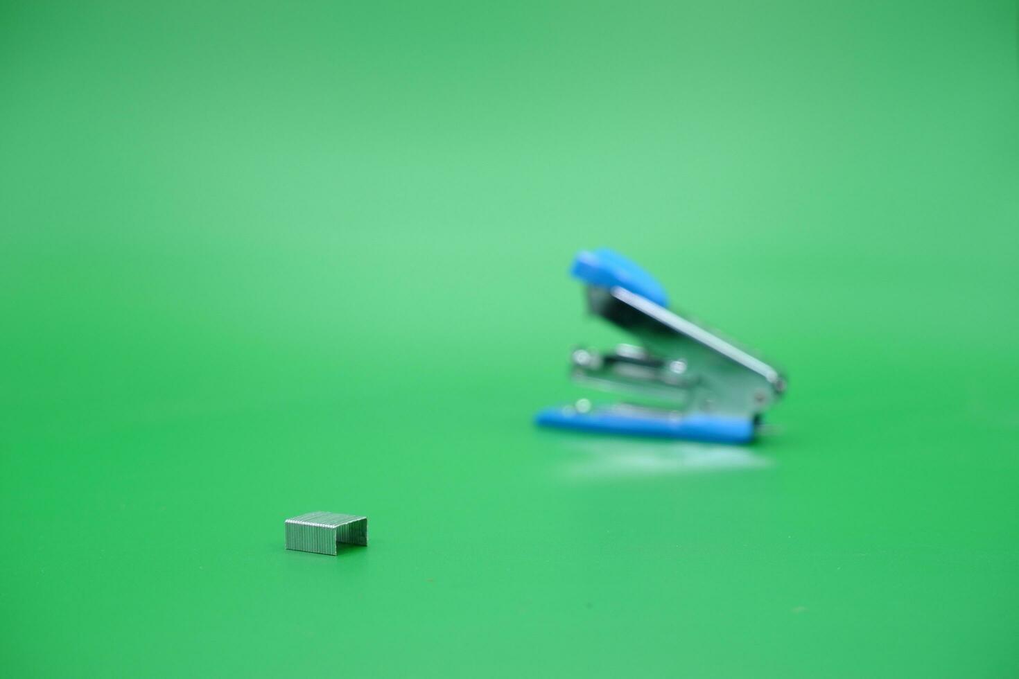 stapler refill and blurred stapler isolated green background. photo