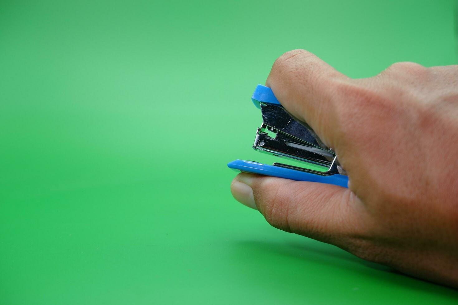 hand holding stapler isolated on green background. photo