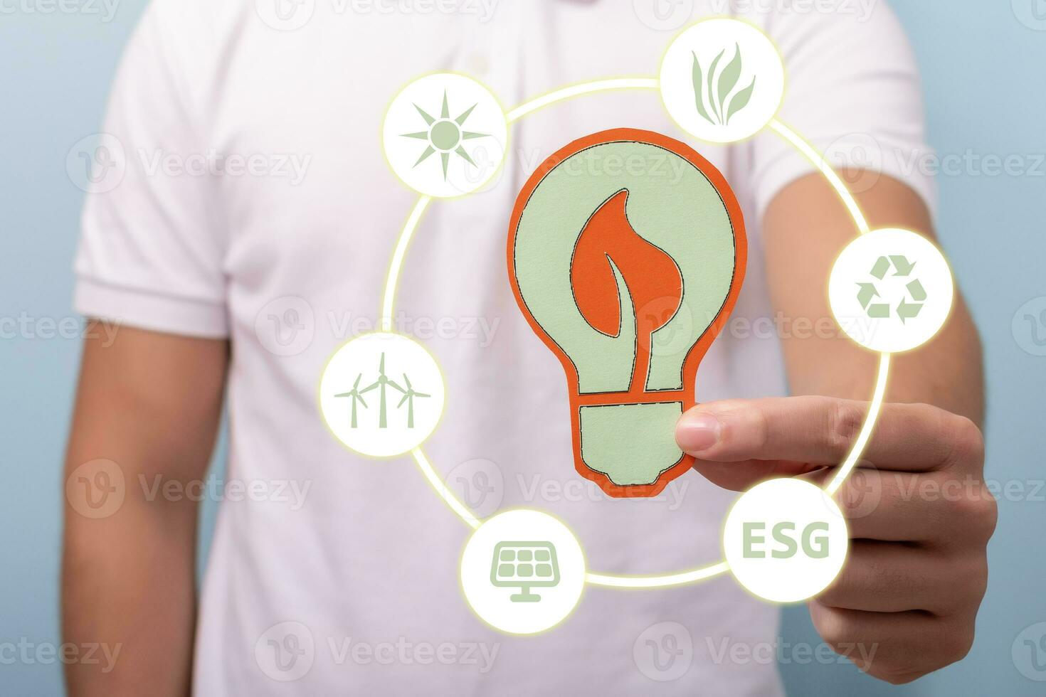 Hand holding cardboard silhouette of a light bulb with icons energy sources for renewable, sustainable development. Ecology concept. photo