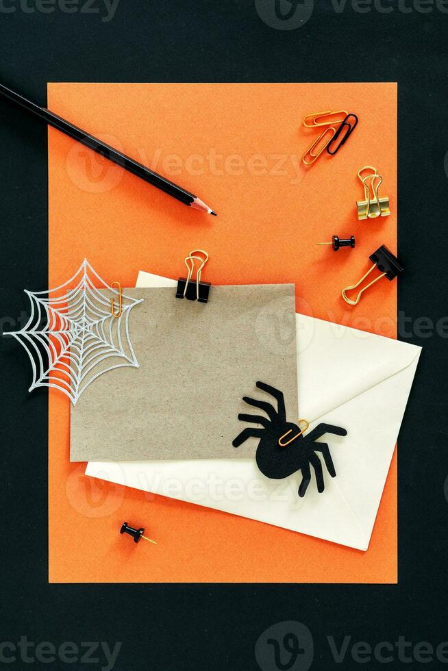 Autumn Fall Halloween theme desktop workspace with card, envelope, pencil, clips on stylish orange textured background. photo