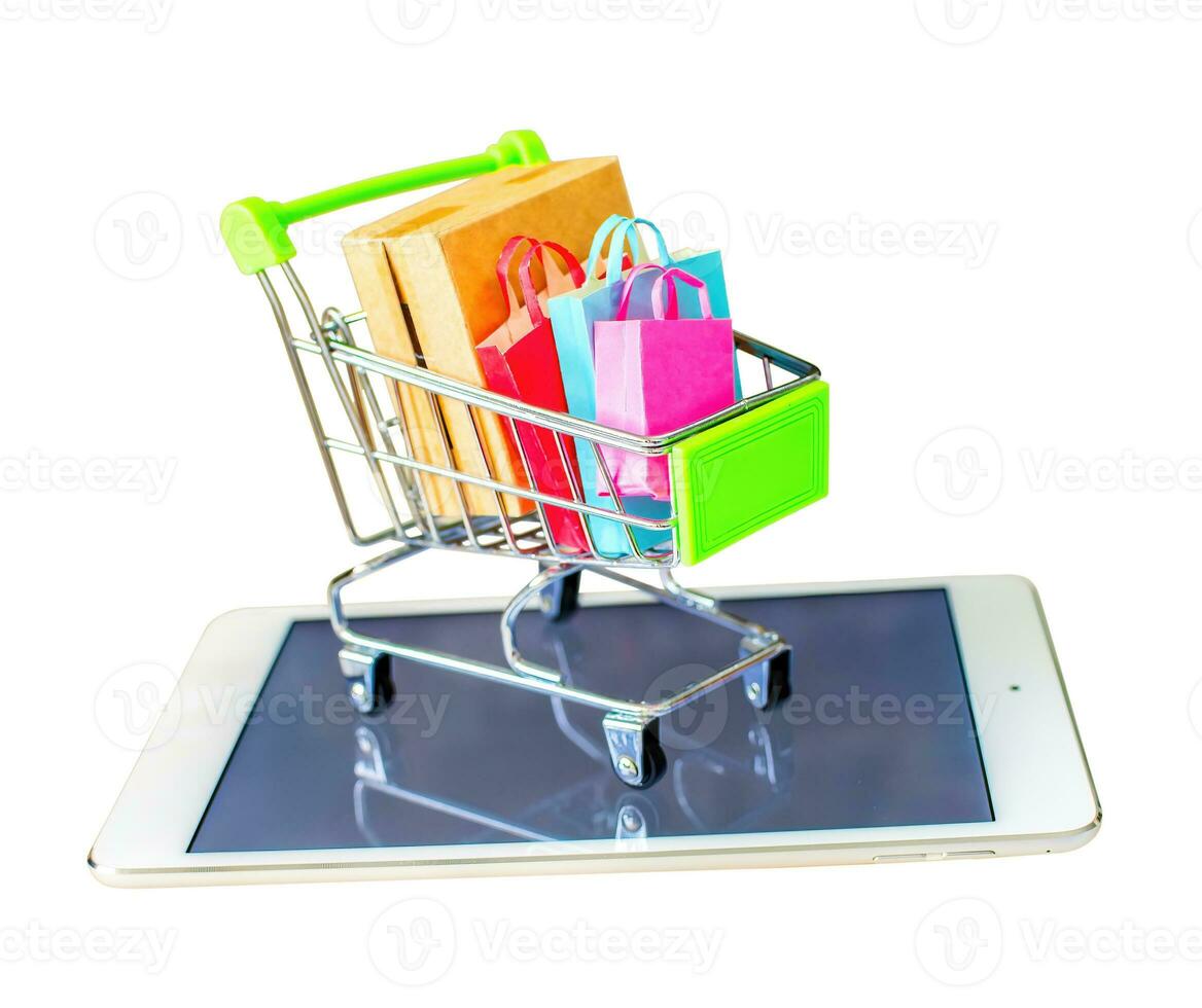 Product package box and shopping bag in cart with tablet which web store shop on screen for online shopping and delivery concept. photo