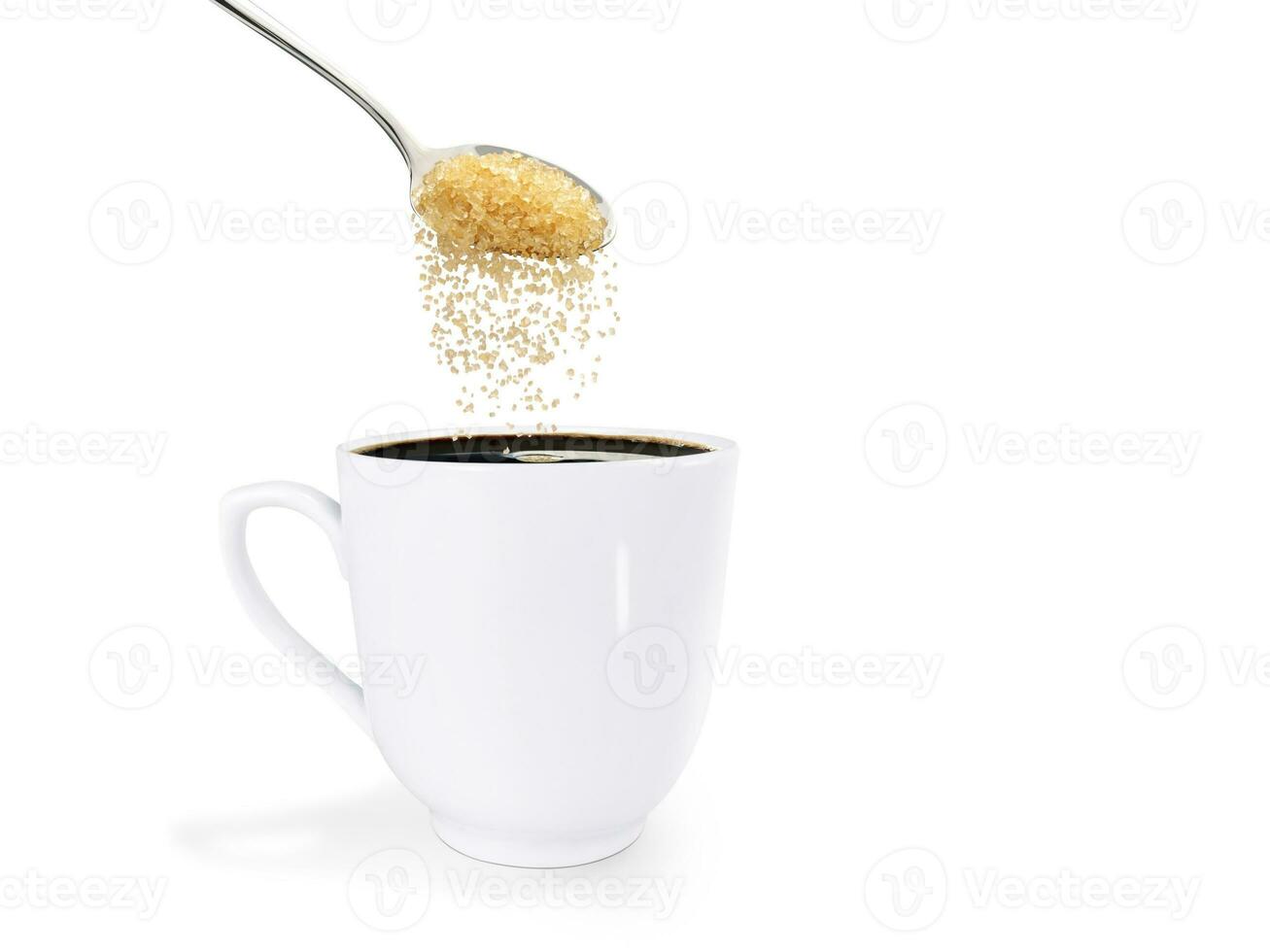 A spoonful of granulated sugar is poured into a white coffee mug. isolated on white background photo