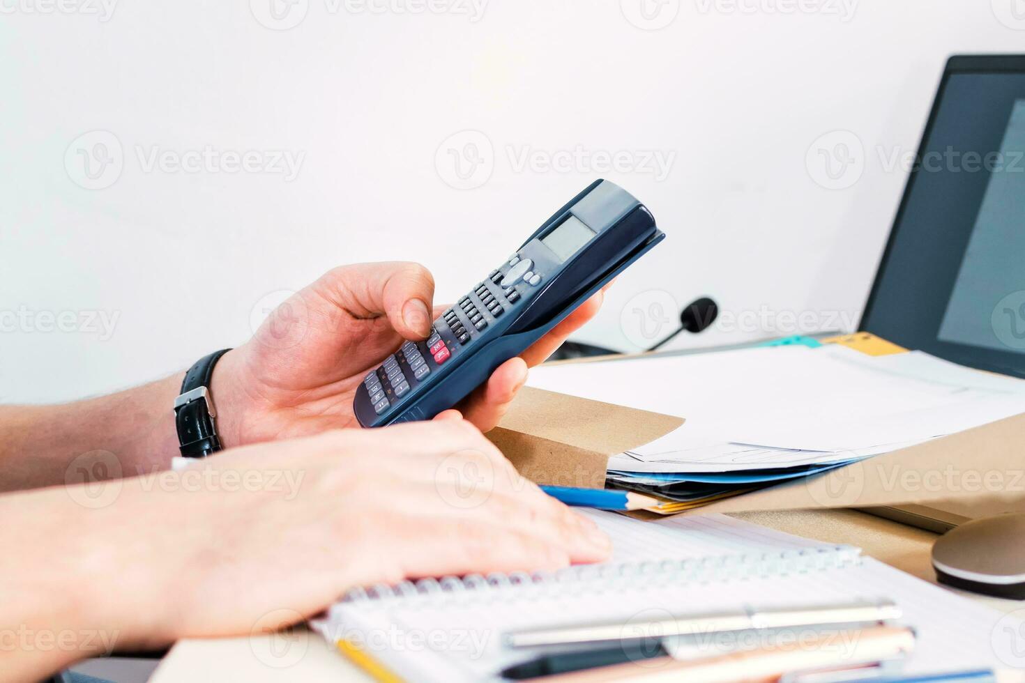 Businessman doing accounting and calculating with a calculator in a desktop at office. Side view. photo