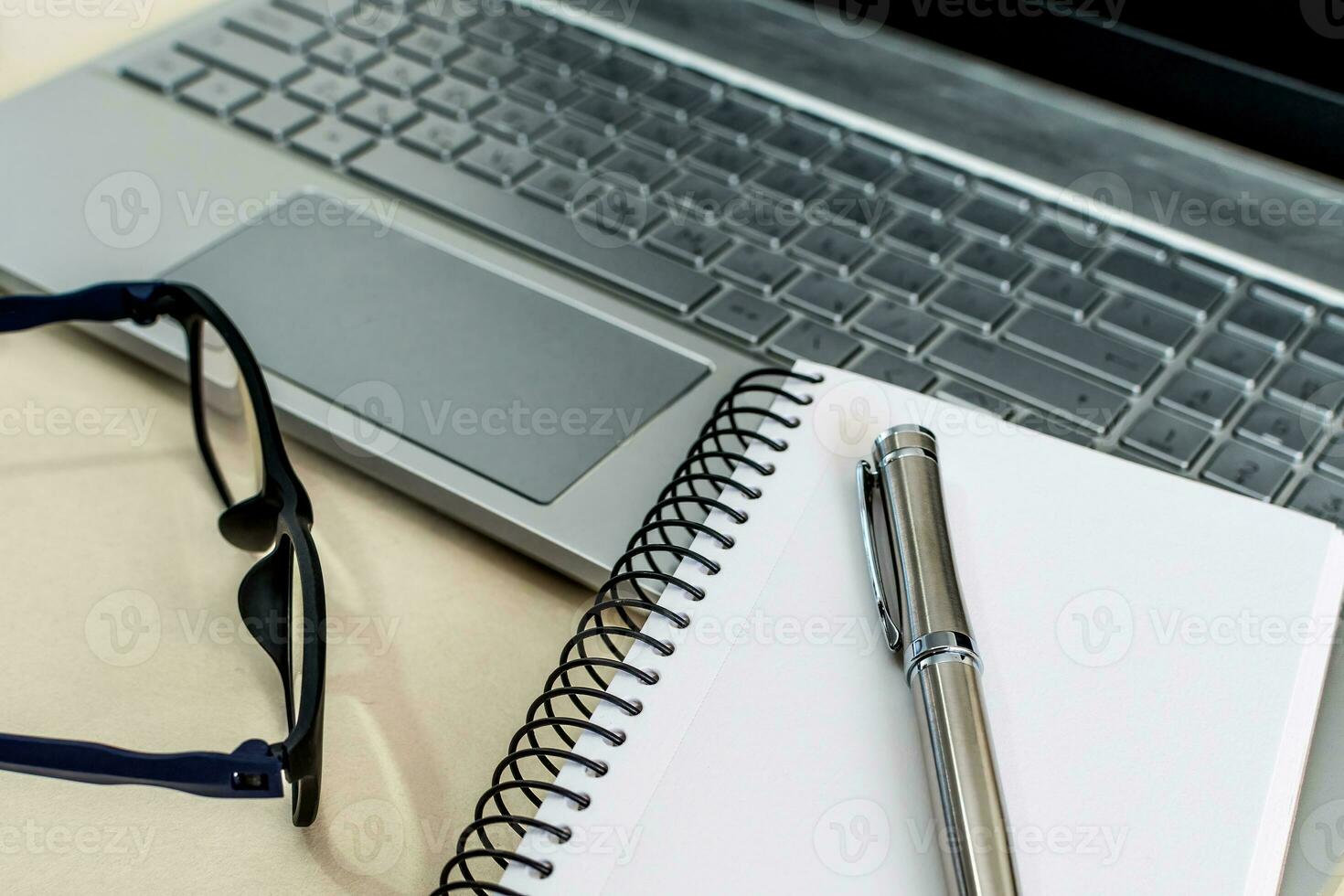 Blank notepad is on top of office desk table with laptop computer and supplies. photo