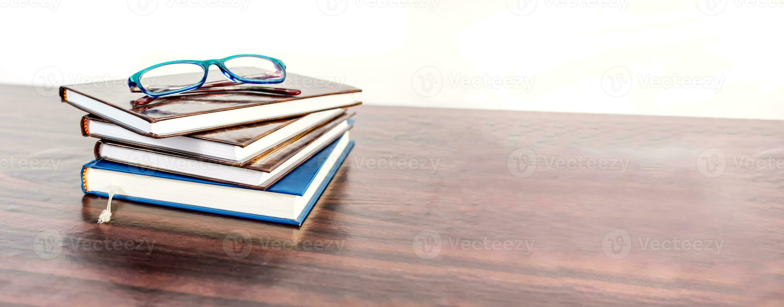 apilar de libros con leyendo lentes en de madera escritorio. educación bandera. foto