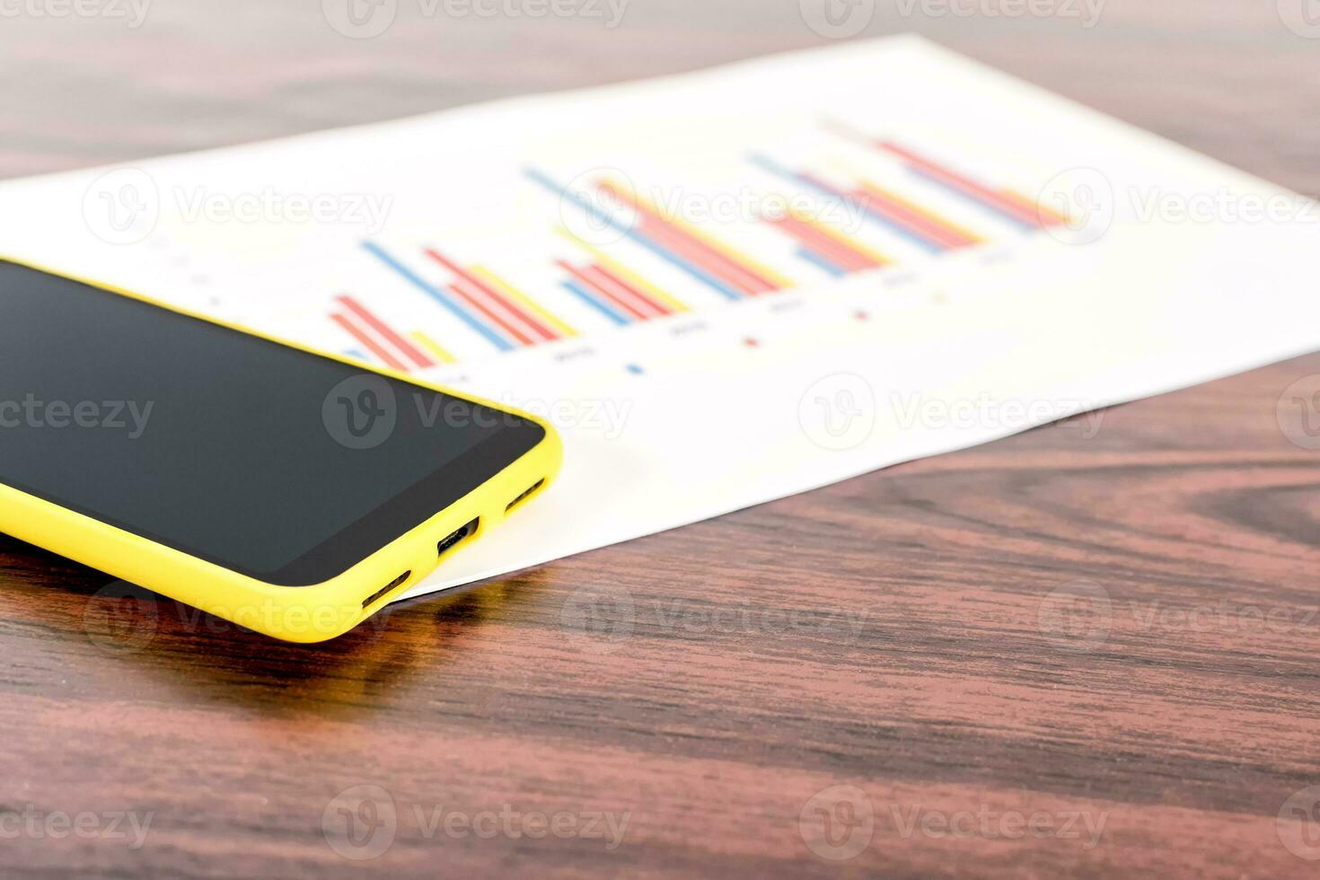 mobile phone with blank black screen with statistic graph on desk. photo