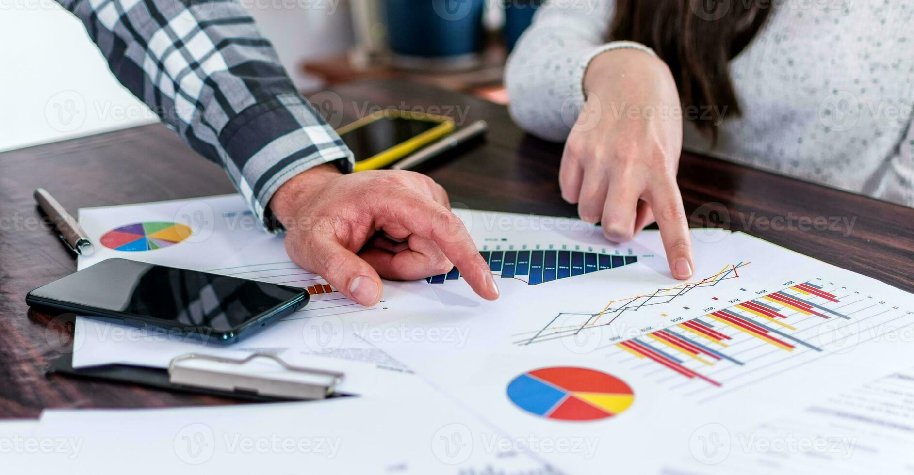 Two businesspeople analyzing graphs, without faces, analyzing data with investor at home office. Selective focus. photo