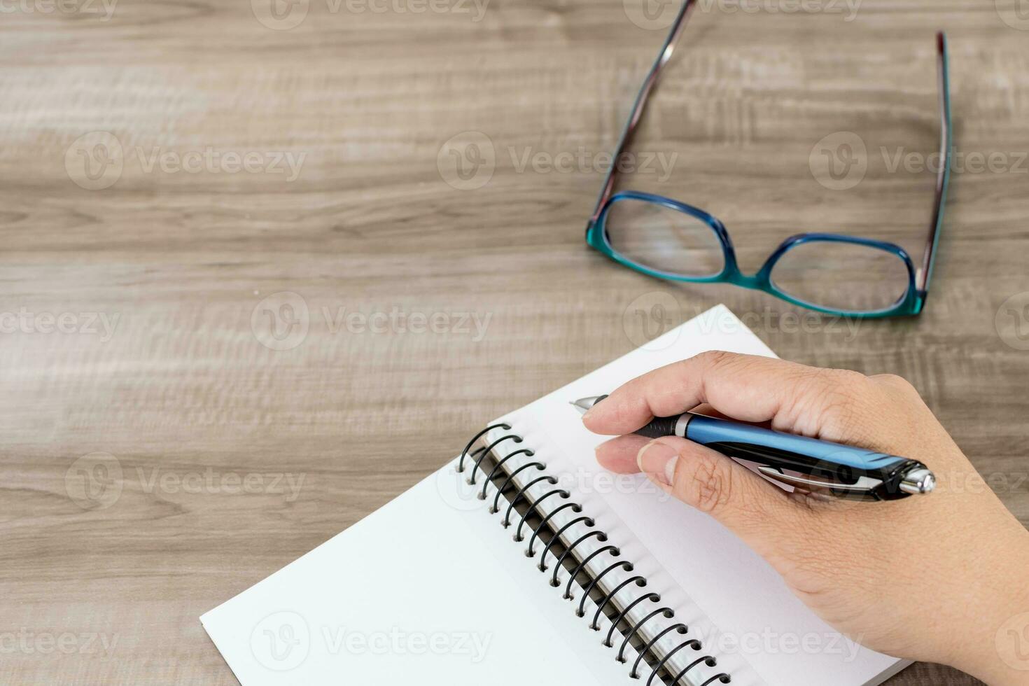 Female hand with notebook on wooden desk. Business, education and people concept. photo