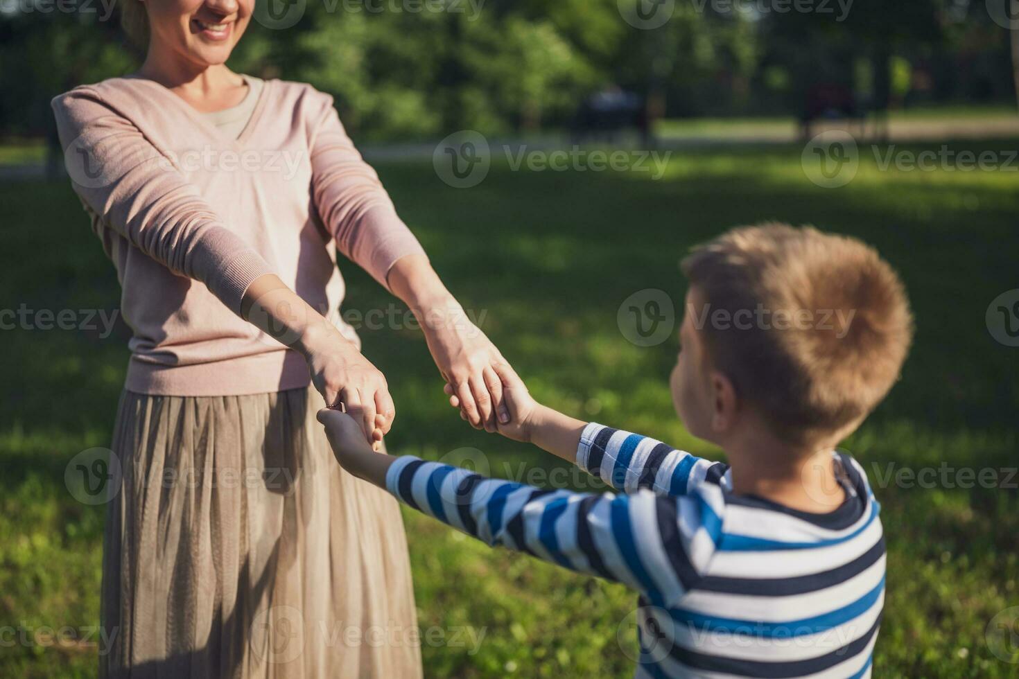 contento madre es jugando con su hijo en parque. ellos son participación manos. foto