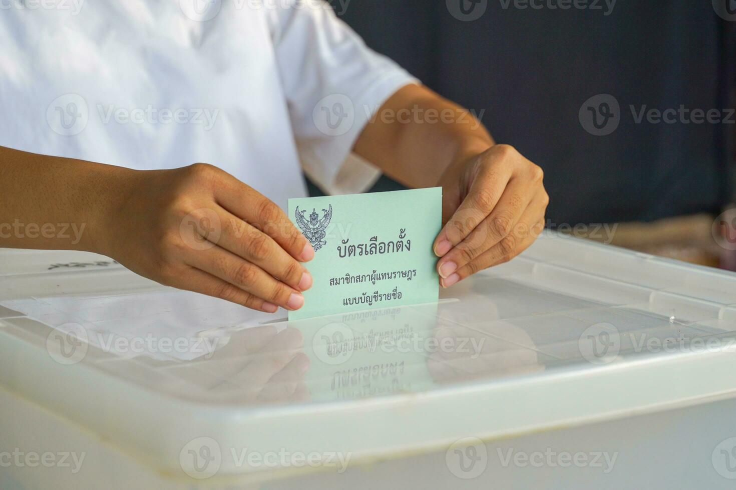 Thai people drop their ballot papers into the box to vote for members of the House of Representatives. The ballot papers are written in Thai,meaning Party-list proportional representation ballot paper photo