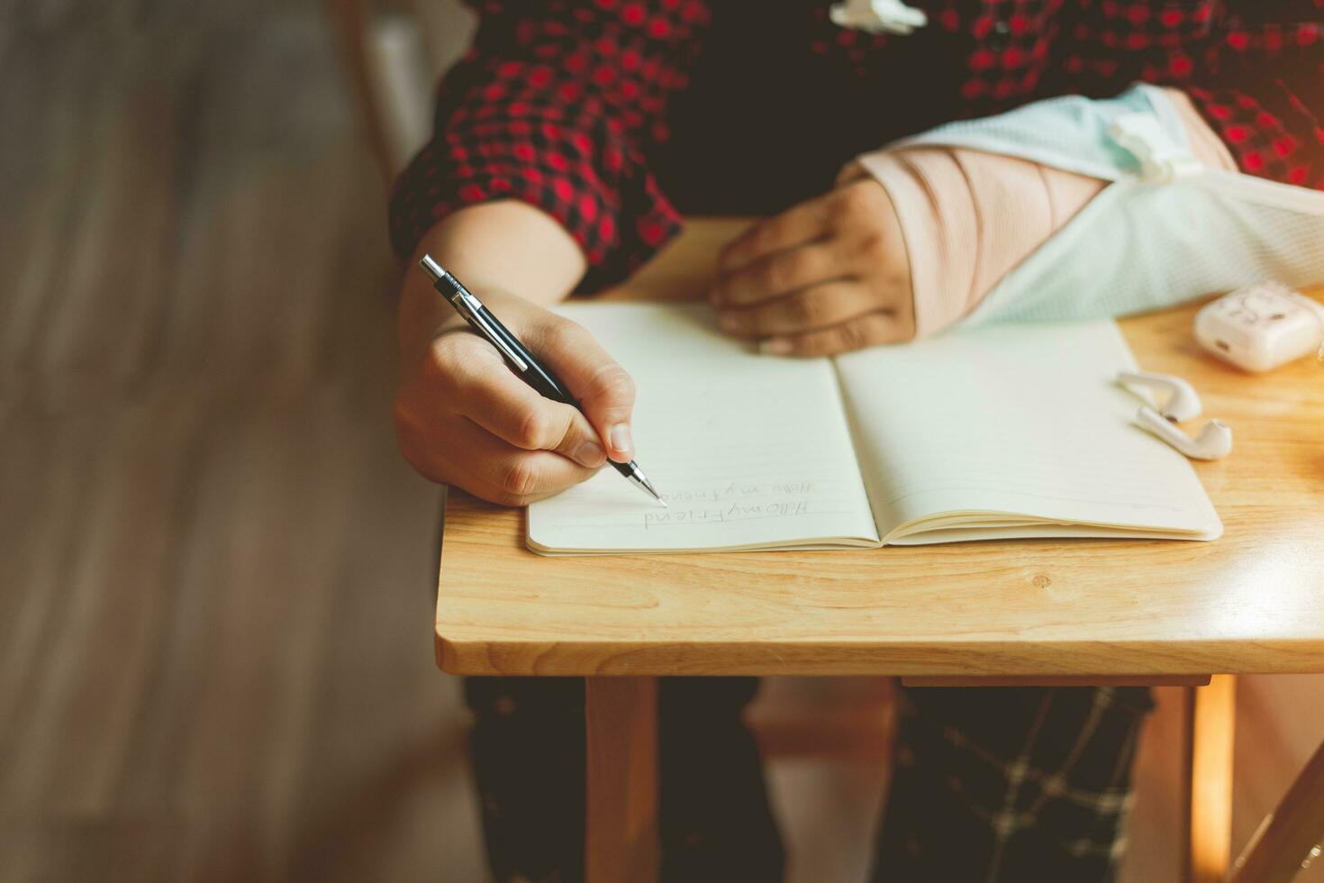 Hands of male students describe Greetings Hello Letters to classmates, His right arm was put on a splint while sitting at home absent from school message writing essay study and student friend concept photo