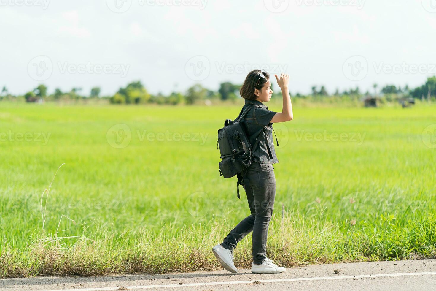 Woman with backpack hitchhiking along a road photo