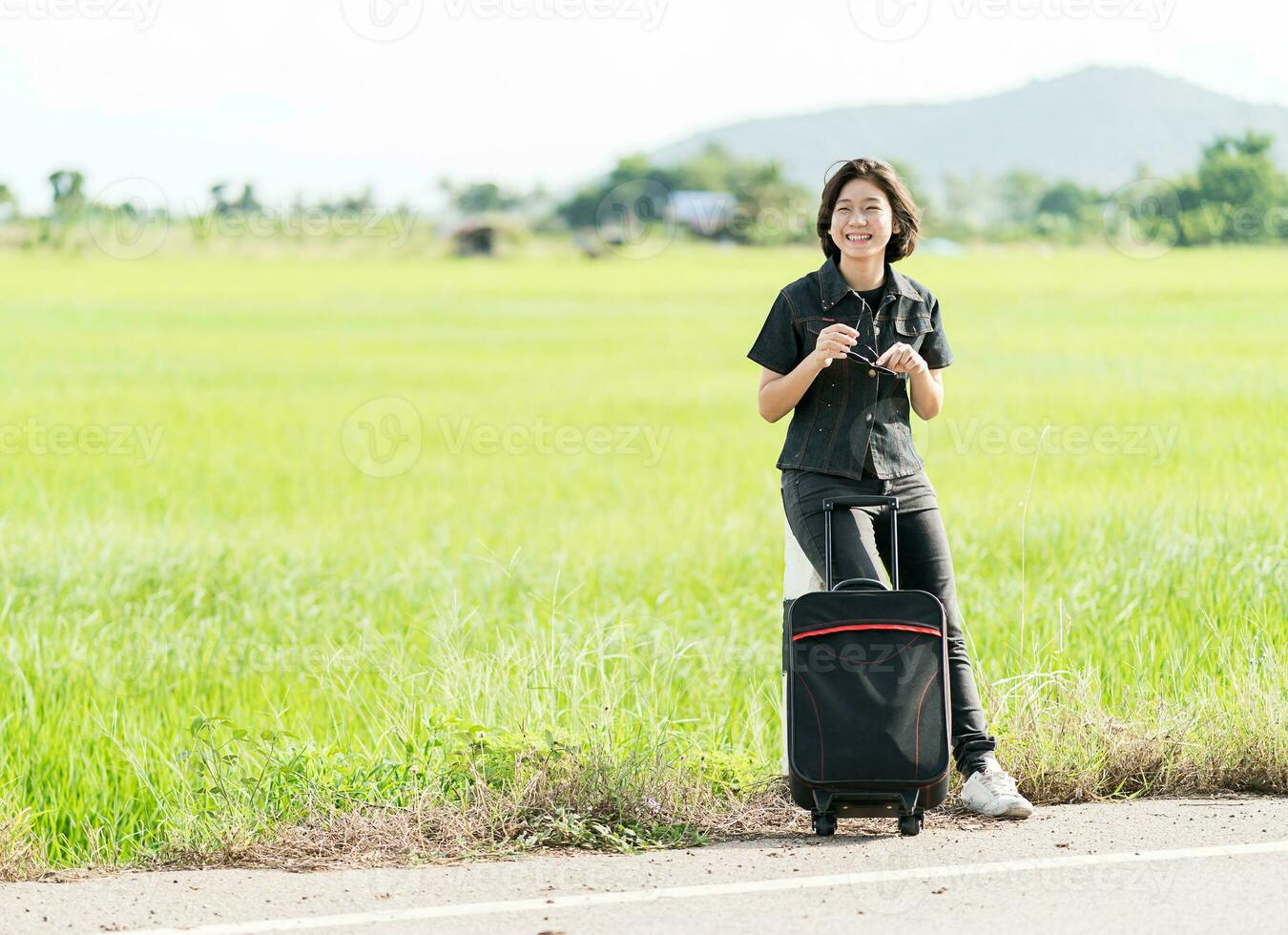 mujer con equipaje haciendo autostop por una carretera foto