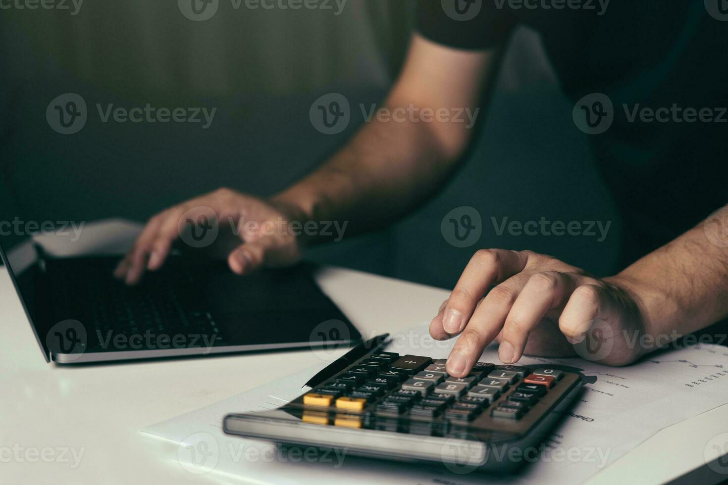 Asian man is using a calculator to calculate his family's monthly miscellaneous expenses at his home. photo