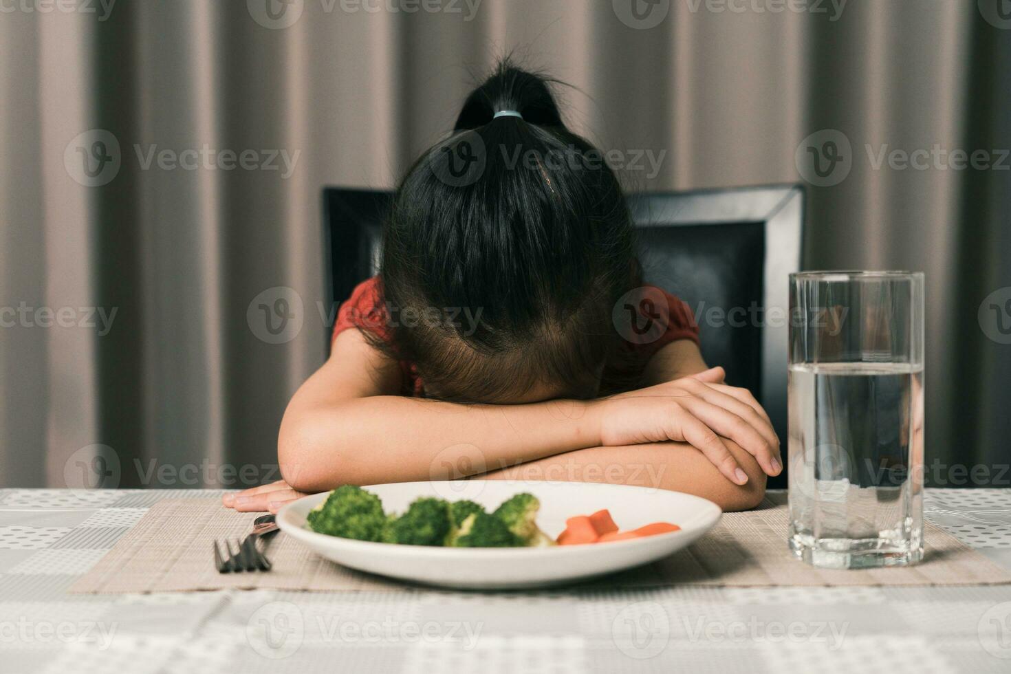 Little cute kid girl refusing to eat healthy vegetables. Children do not like to eat vegetables. photo