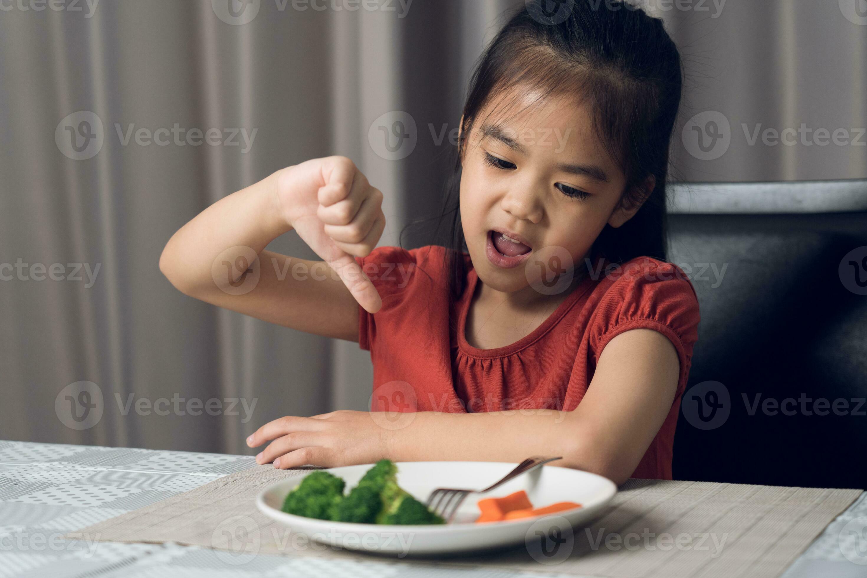 Little cute kid girl refusing to eat healthy vegetables. Children do not like to eat vegetables