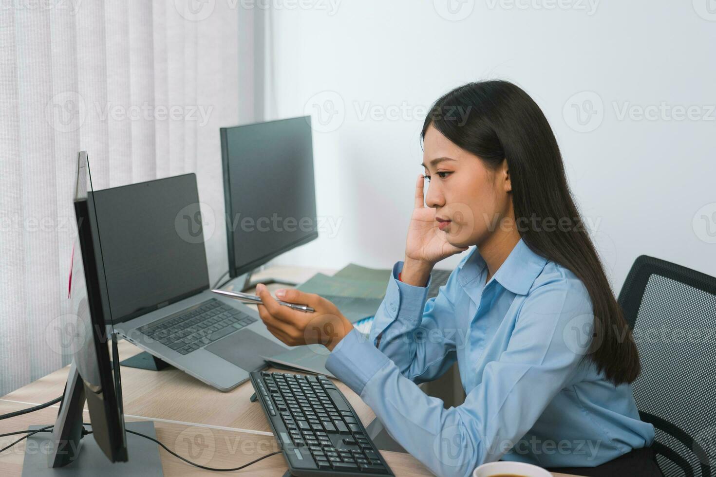 Concentrated asian woman brainstorming while coding data on desktop PC while working on computer codes in the office. photo
