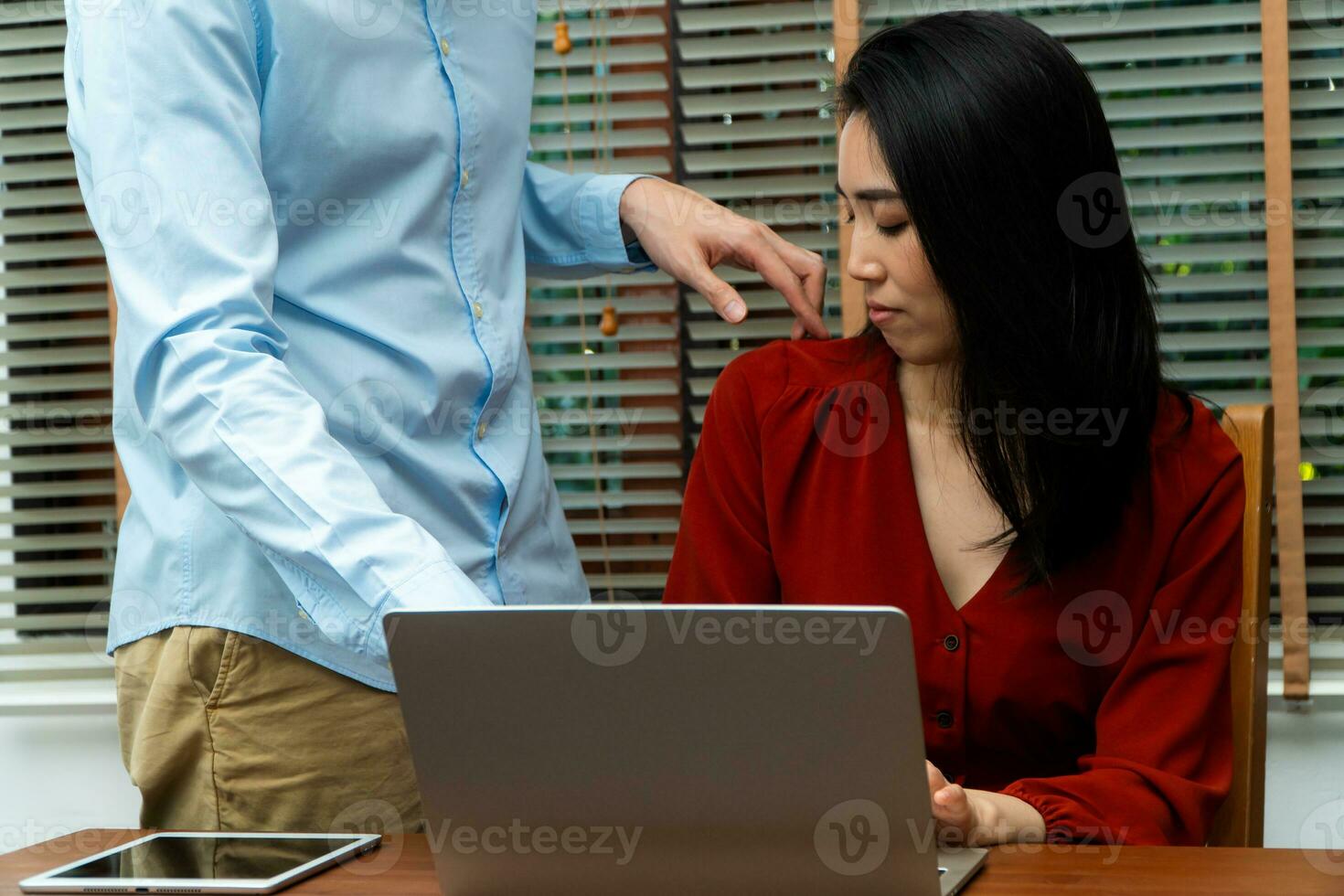 Boss touching shoulder of a young female employee in office at workplace. She is uncomfortable and afraid of sexual inappropriate abuse from a colleague. Concept of sexual harassment in the workplace photo