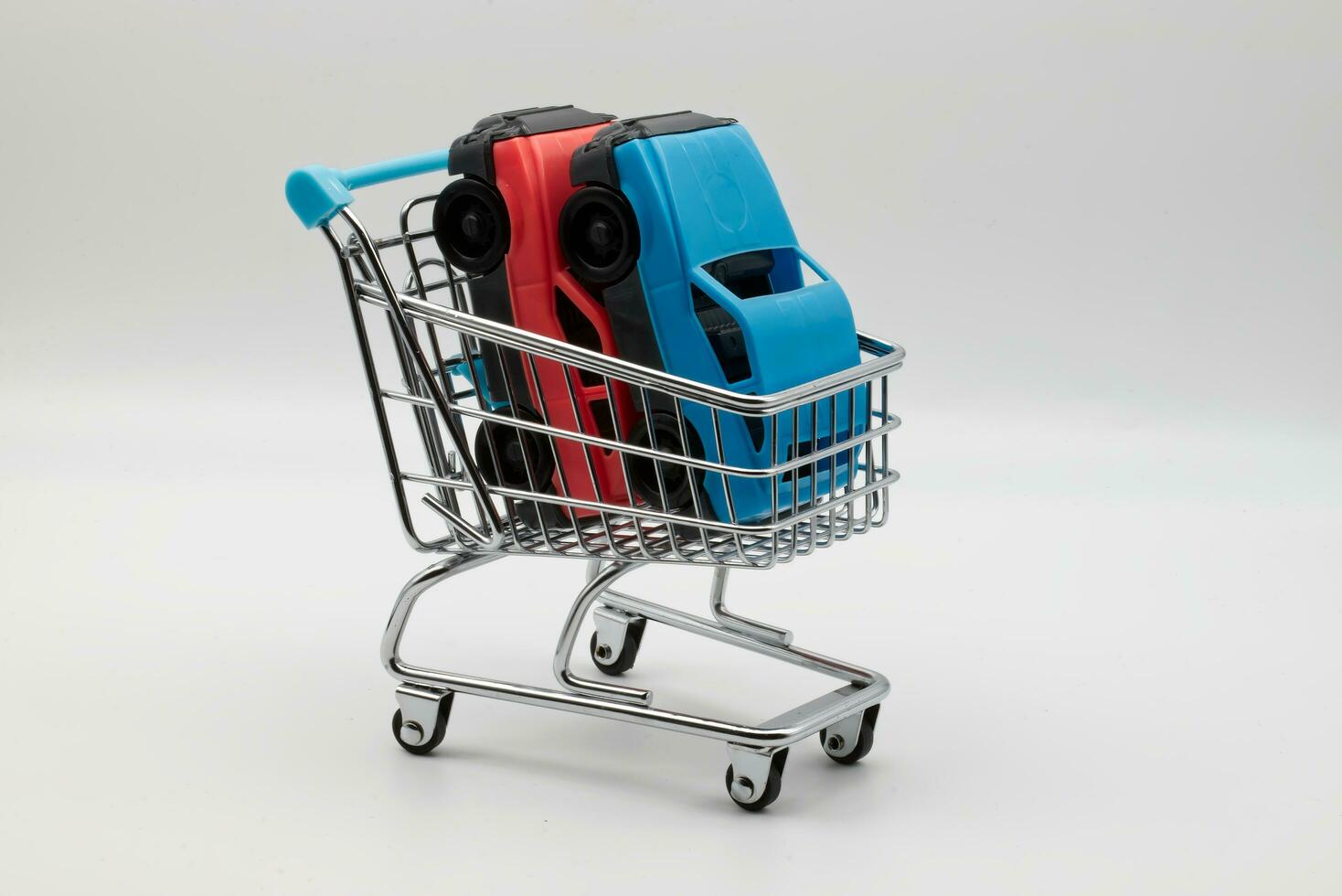 Car models inside a shopping trolley. Concept of increasing consumerism in our modern society photo