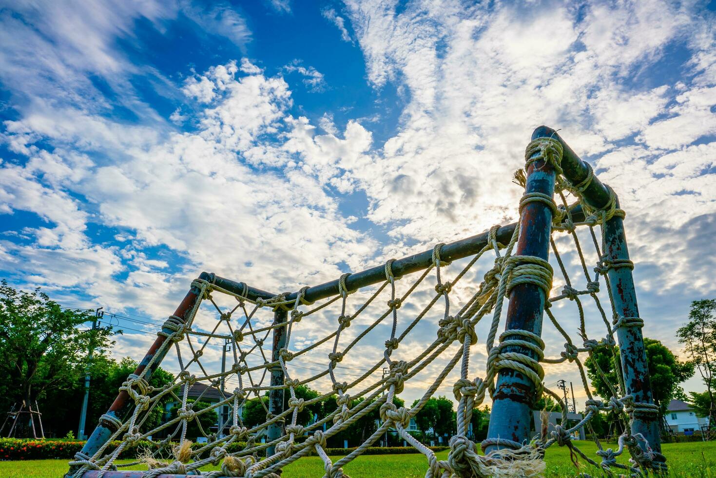 Rope net goal, mini soccer field with green grass Simple, old-fashioned miniature mosquito nets woven with straw clutter up the park sky and white clouds background, selective focus, soft focus. photo