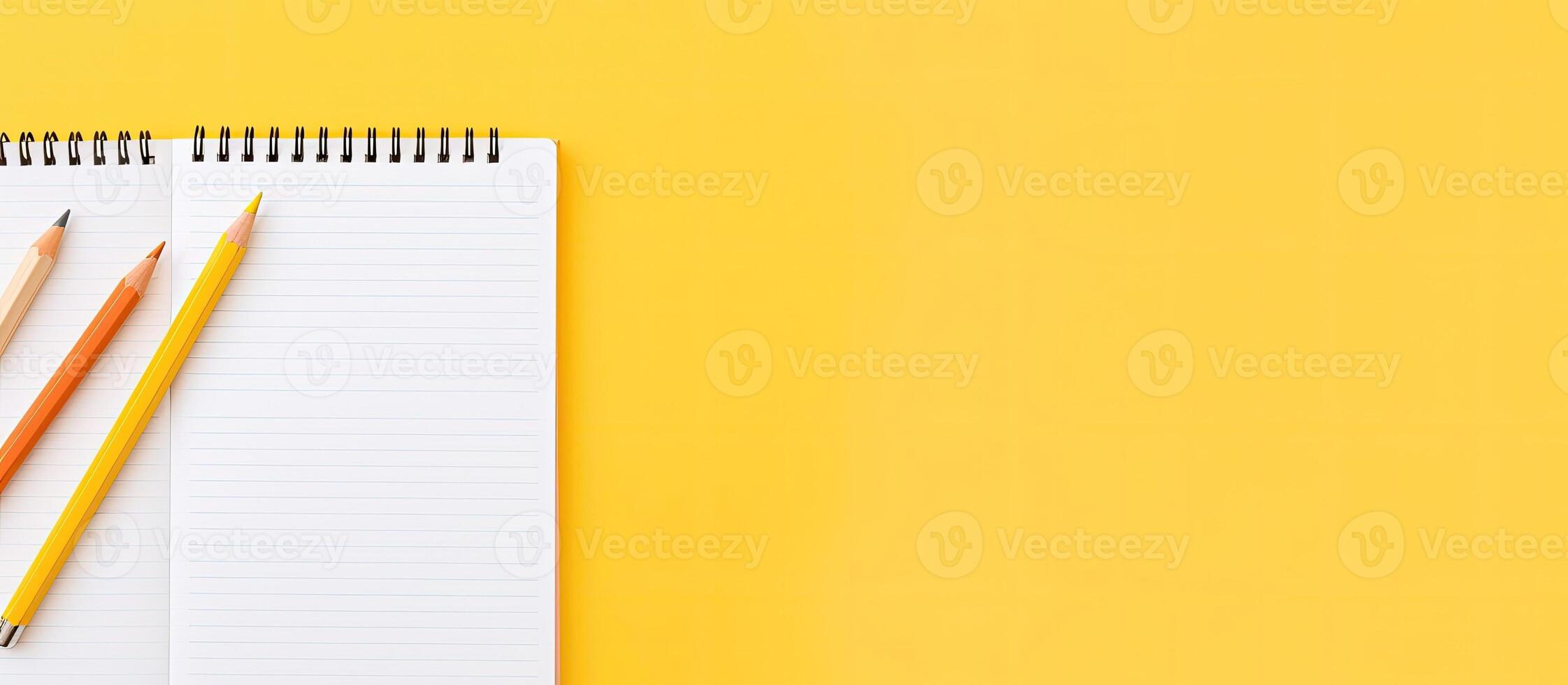 Two pencils and a notepad on a yellow background created with technology photo