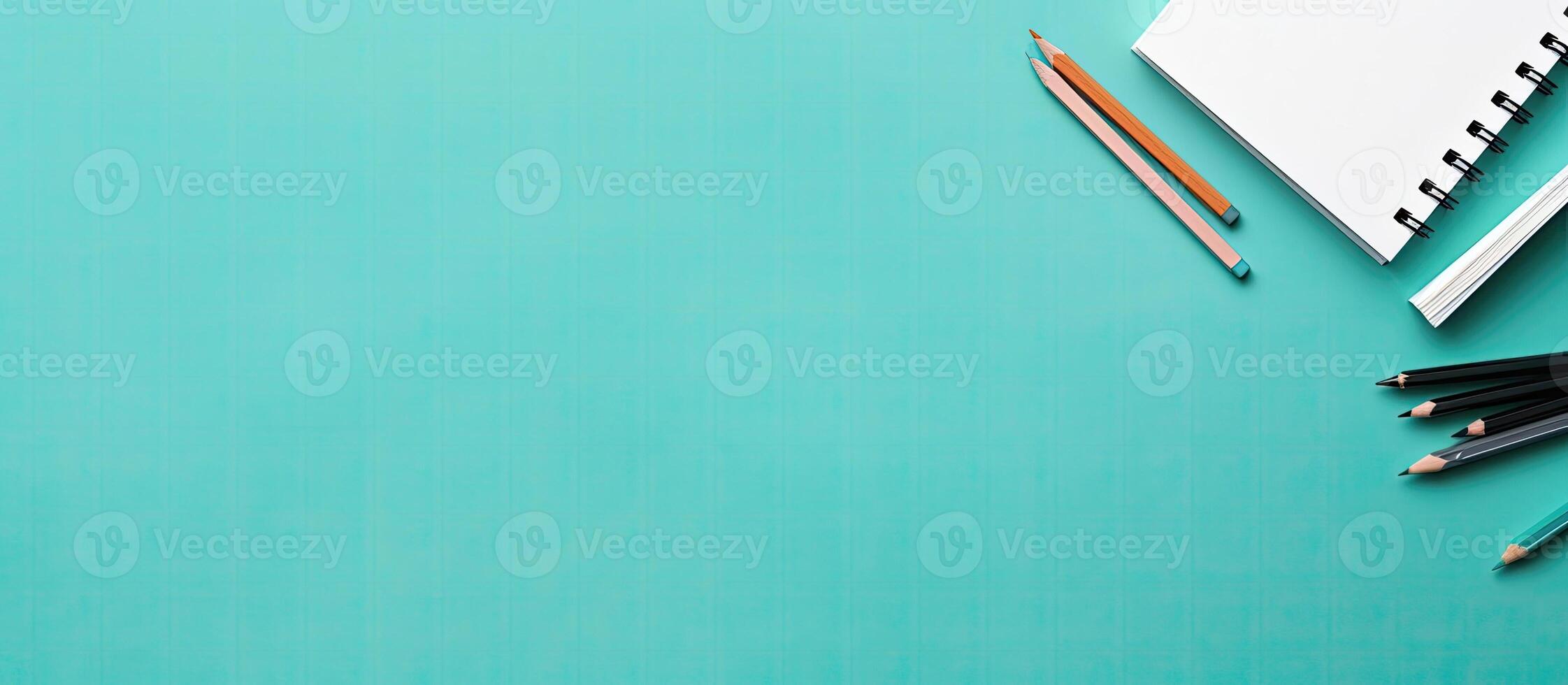 A notebook, pencils, and a pair of scissors on a turquoise background created with technology photo