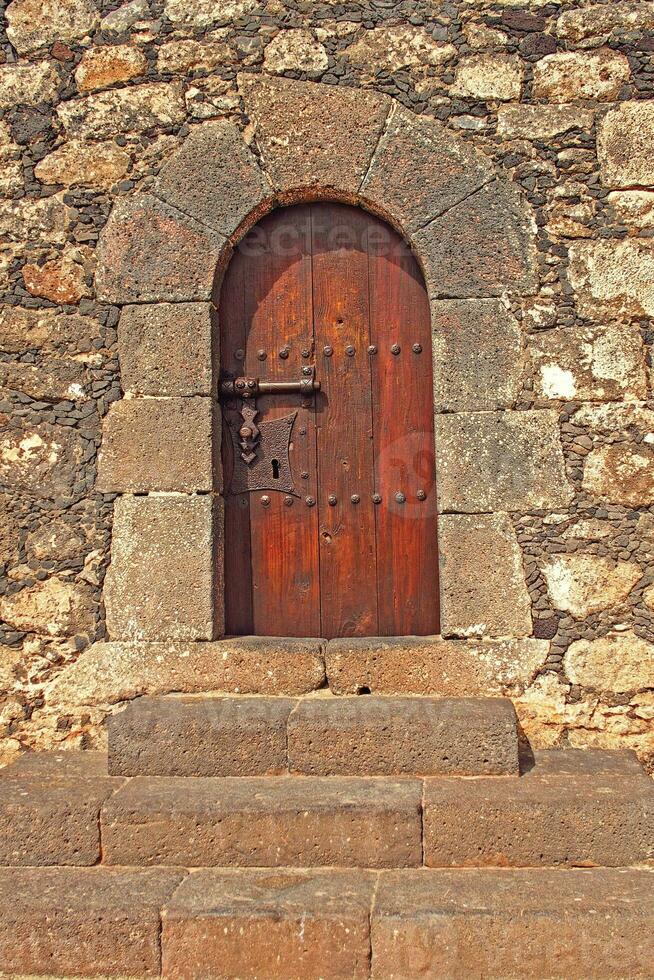 antiguo de madera puerta con metal guarniciones en un Roca edificio creando un antecedentes con escalera foto