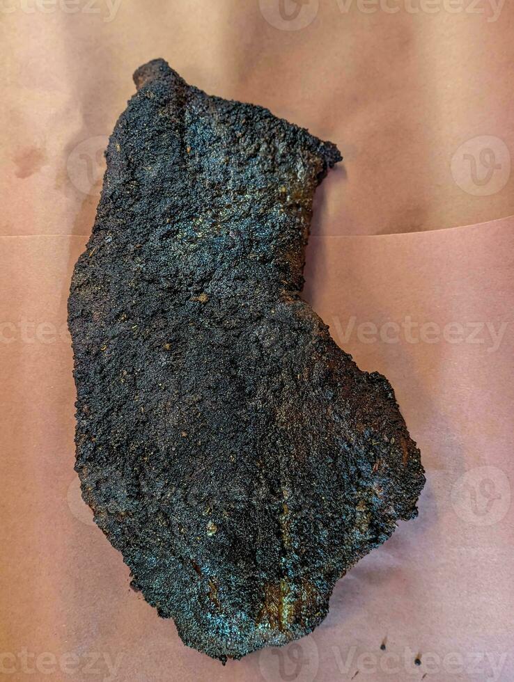 A large piece of smoked beef brisket on the ribs with a dark crust. photo