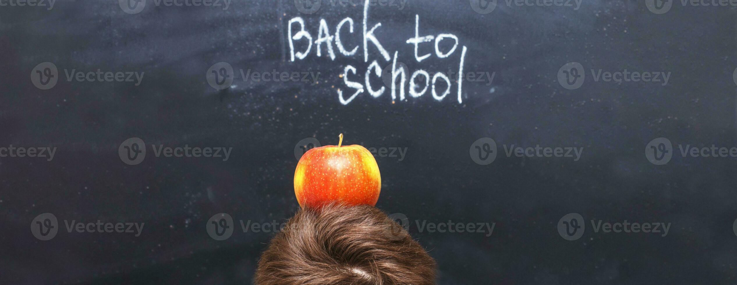 an apple on a child's head near chalkboard. Back to school concept background photo