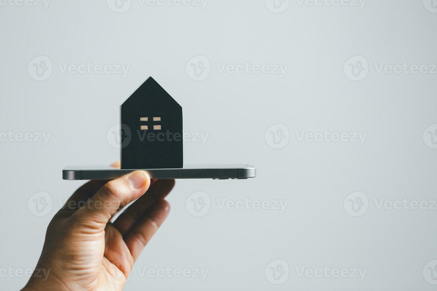 Hand holding mobile computer shows the house model. The concept of management of real estate. House model with real estate agent professional making business and mobile phone. photo