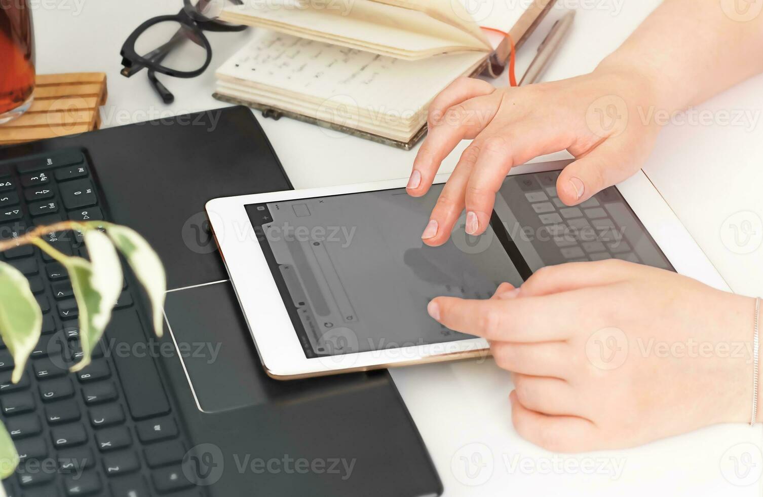 Work from home. Female hands with tablet at the table closeup photo