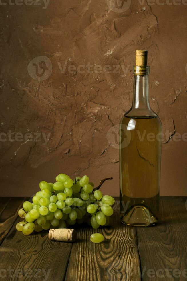 Glass bottle of wine with corks on wooden table background photo