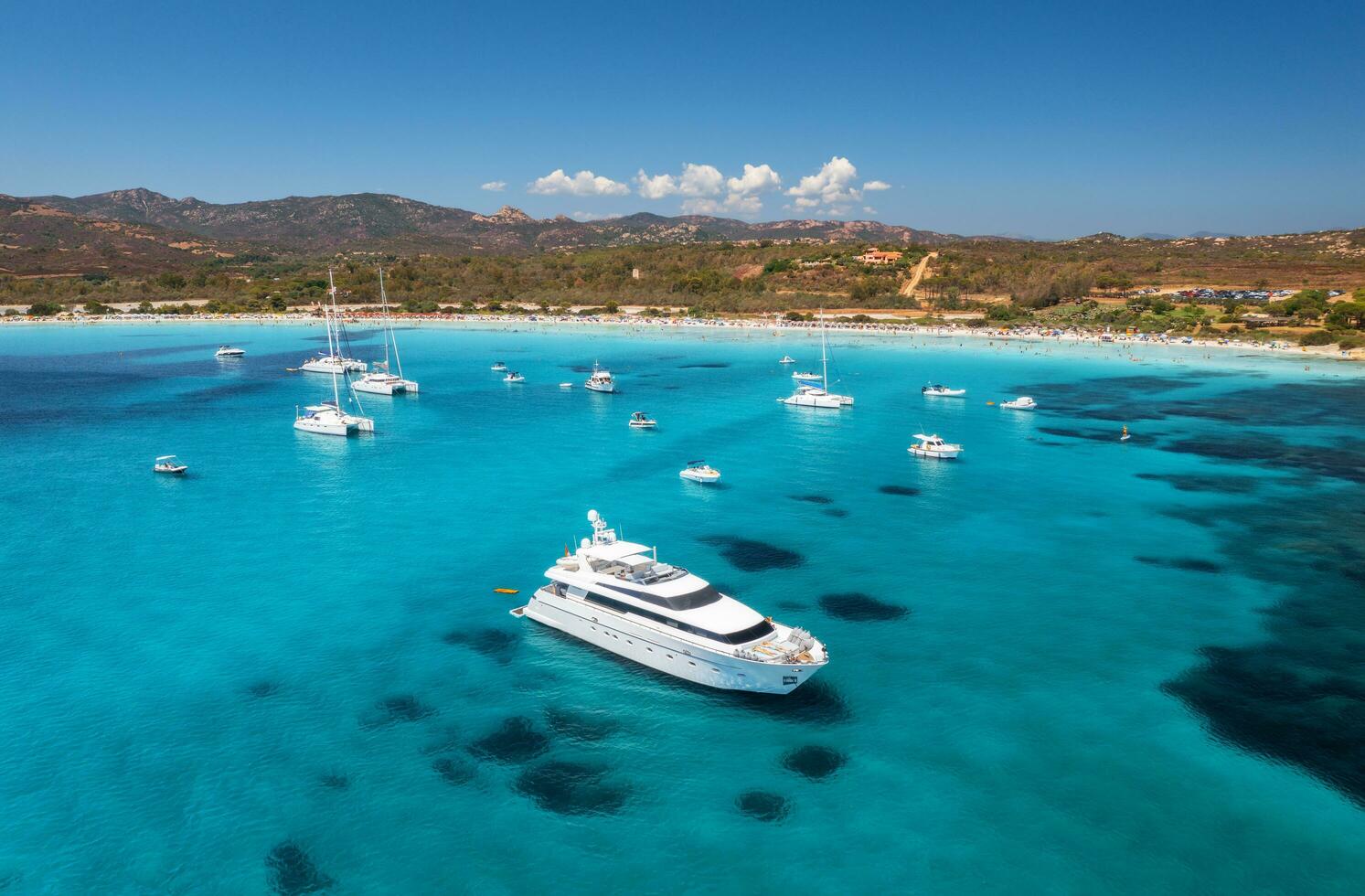 Aerial view of luxury yachts on blue sea and sandy beach photo