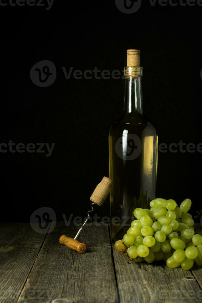 Glass bottle of wine with corks on wooden table background photo