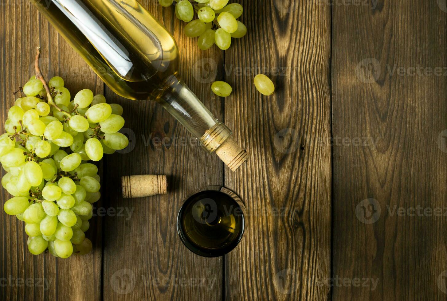 Glass bottle of wine with corks on wooden table background photo