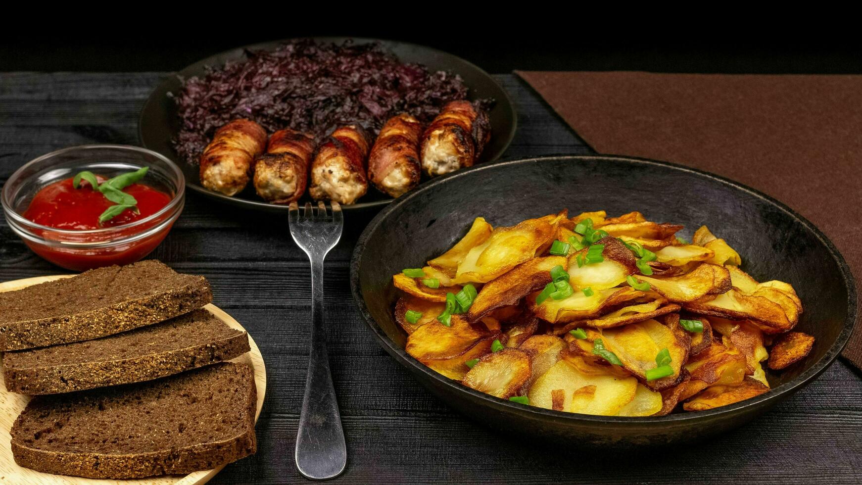 Roasted potato in the pot, pieces of rye black bread on a wooden photo