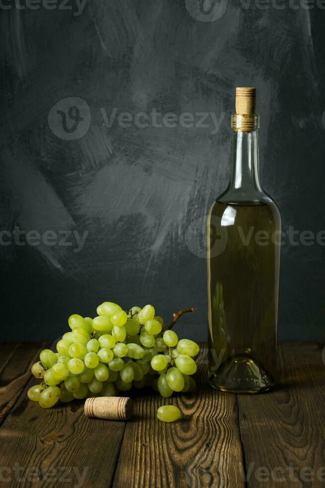 Glass bottle of wine with corks on wooden table background photo