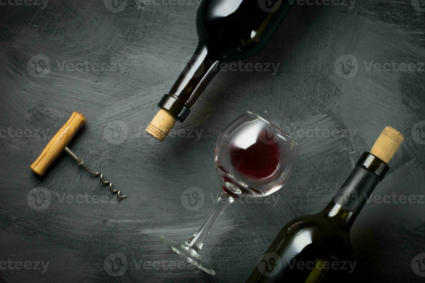 Glass bottle of wine with corks on wooden table background photo