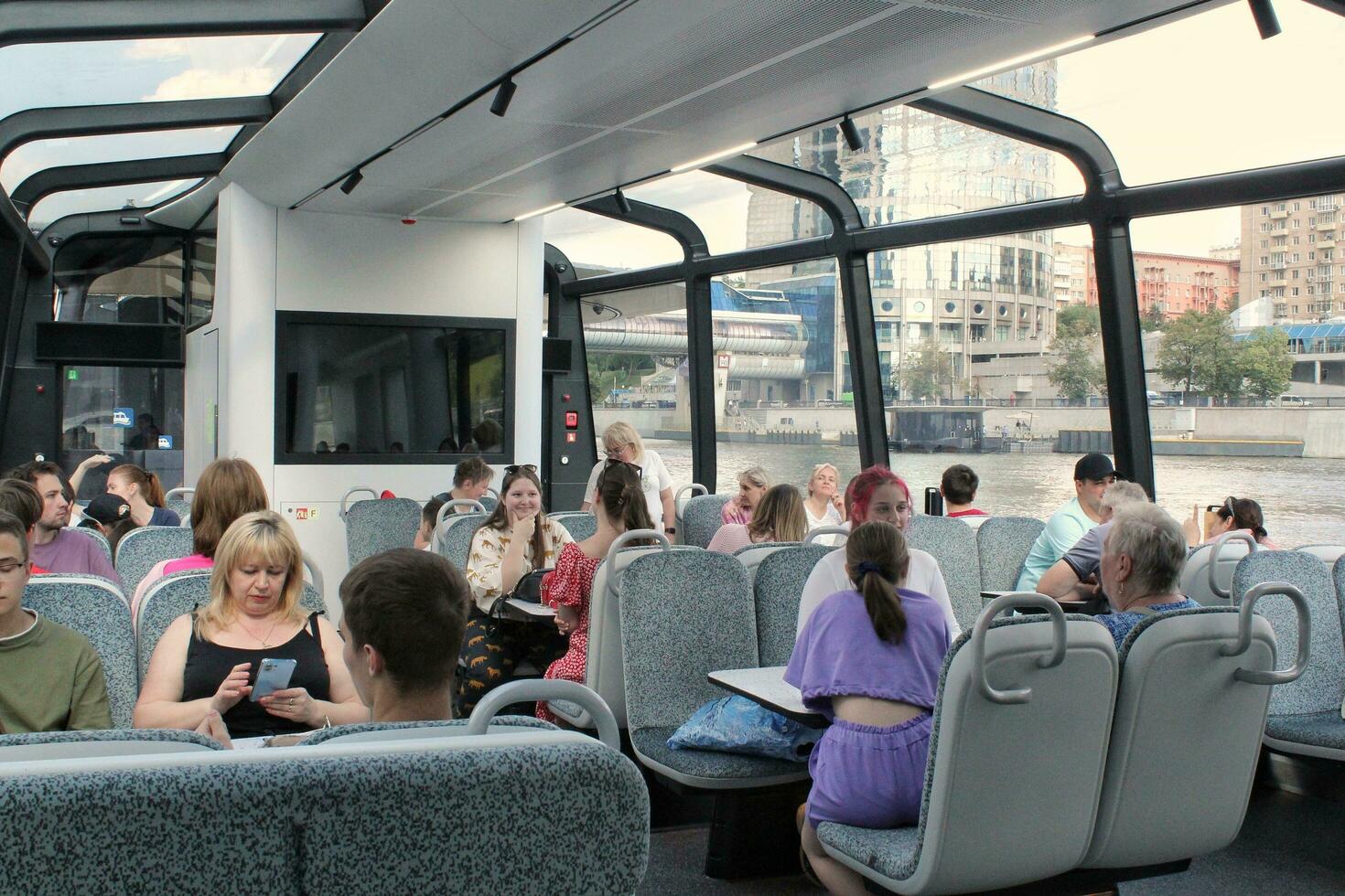 Passengers on a board of aquabus boat on Moskva River. Electrical ship. Ecological public transport . Green energy in city route. Daily passenger ferry service. Moscow, Russia - June 22, 2023. photo