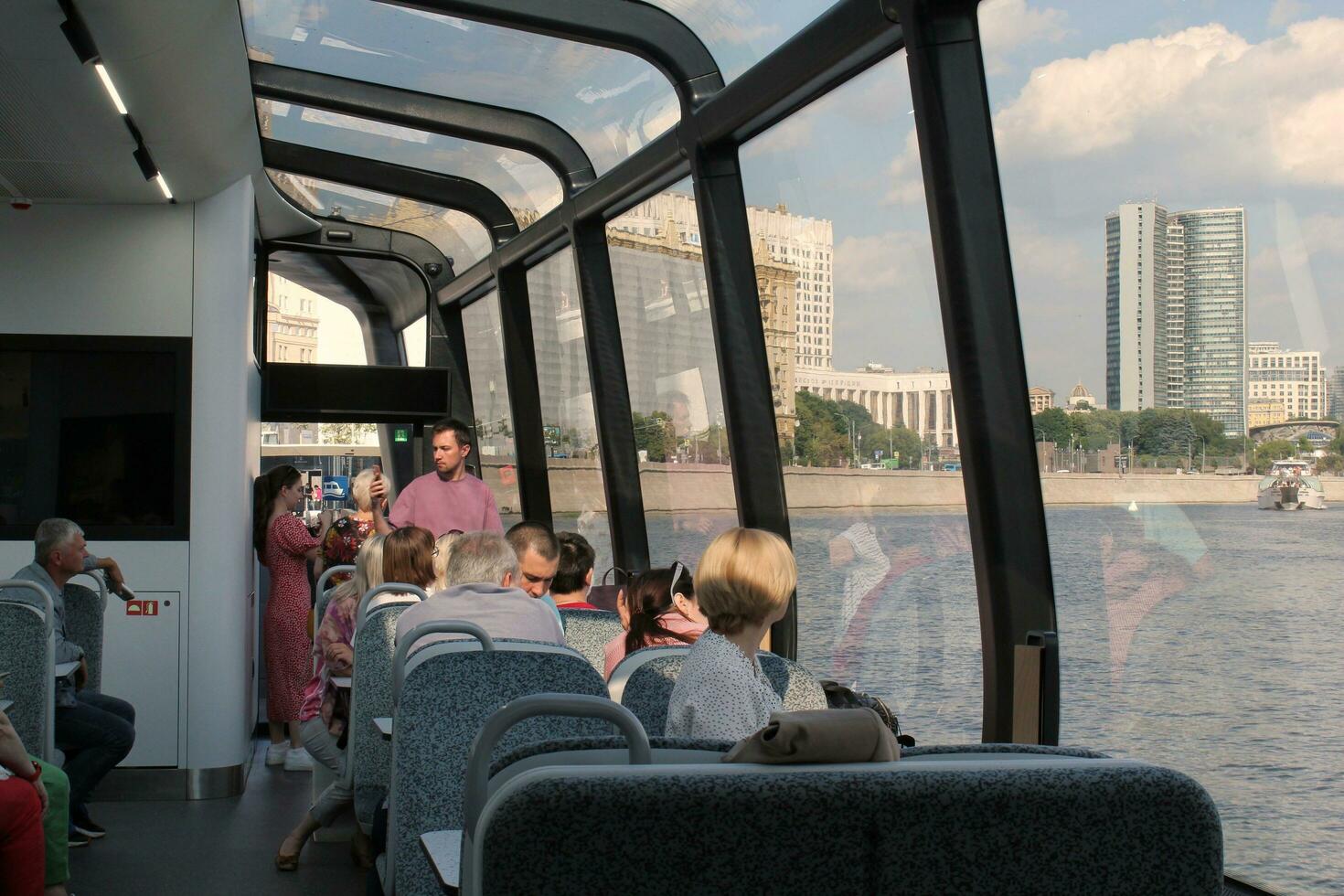 Passengers on a board of aquabus boat on Moskva River. Electrical ship. Ecological public transport . Green energy in city route. Daily passenger ferry service. Moscow, Russia - June 22, 2023. photo