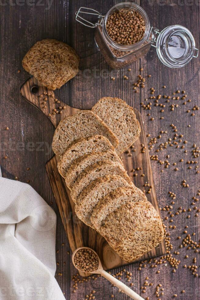 Pieces of homemade buckwheat bread on a cutting board on the table top and vertical view photo