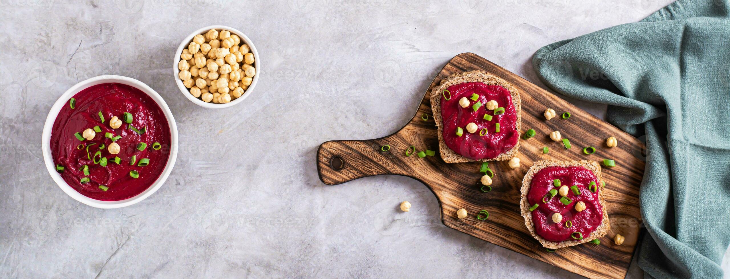 Rye bread bruschettas with beetroot hummus and chives on a cutting board top  view web banner photo