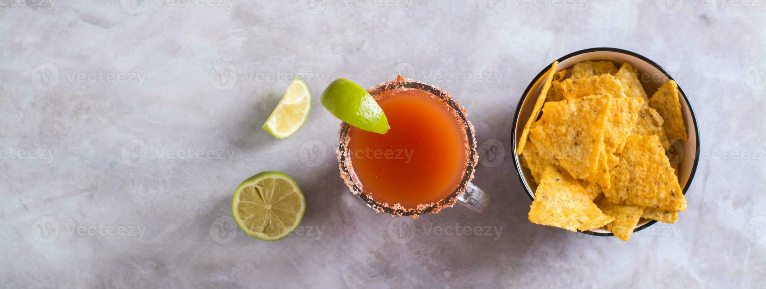 Michelagua mocktail with tomato juice and lime juice in a glass and nachos top view web banner photo