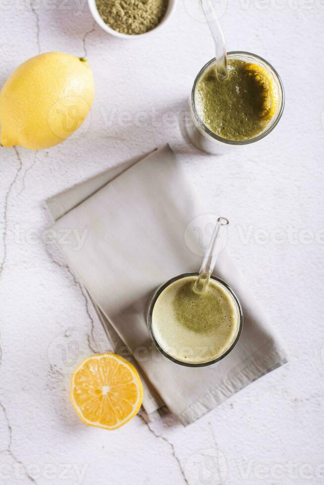 Iced matcha lemonade with lemon in glasses with straws on the table top and vertical view photo