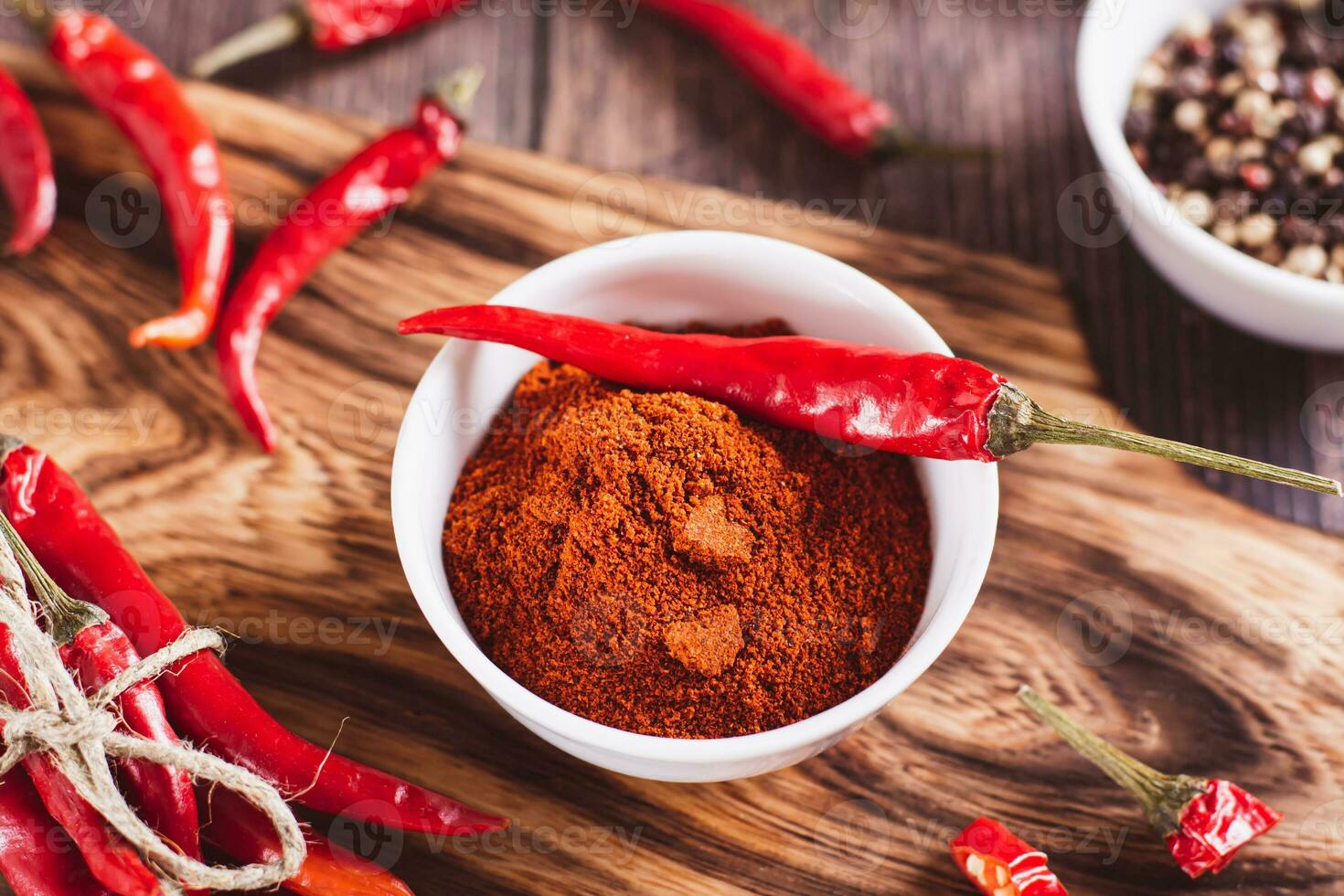 Red raw hot peppers on a bowl with paprika on a wooden background close-up photo