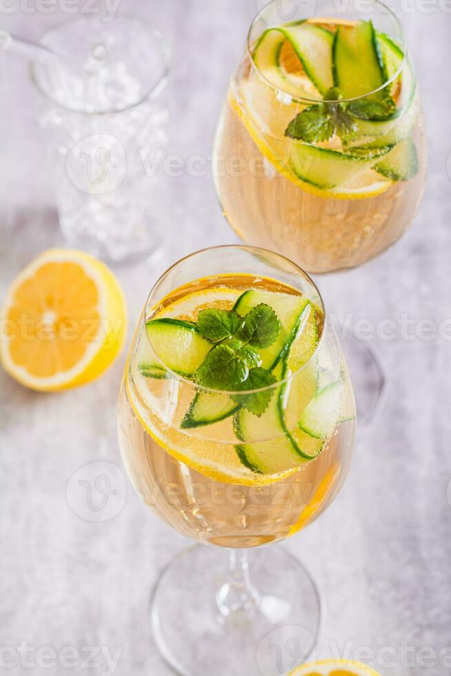 Hugo spritz sparkling cocktail with champagne, cucumber, lemon and mint in wine glasses vertical photo