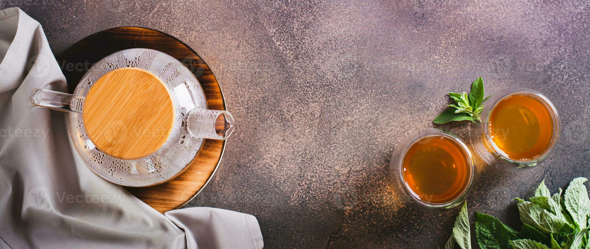 Calming green mint tea in cups and teapot on the table top view web banner photo